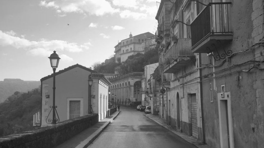 A picturesque street in Ragusa Ibla, showcasing classic Sicilian architecture in black and white.